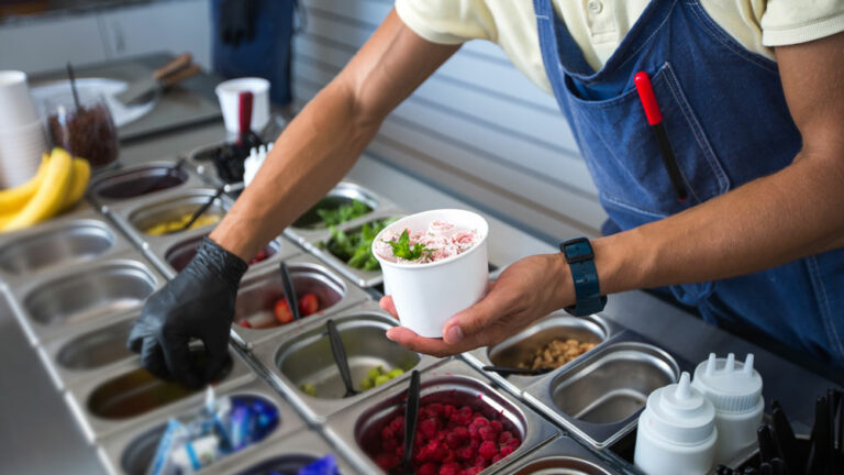 Food service worker adds toppings to ice cream