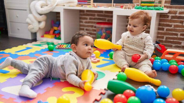 Two babies playing with toys on the floor of a daycare center