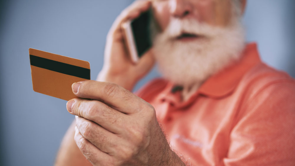 Man on phone while looking at a debit card