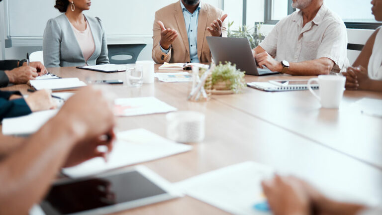 Diverse group of professional people at a conference room table holding a meeting.