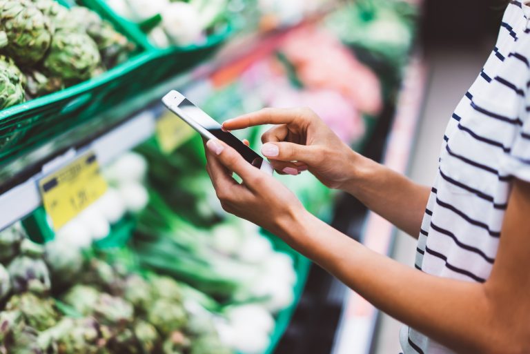 Woman types on her cell phone in a grocery store